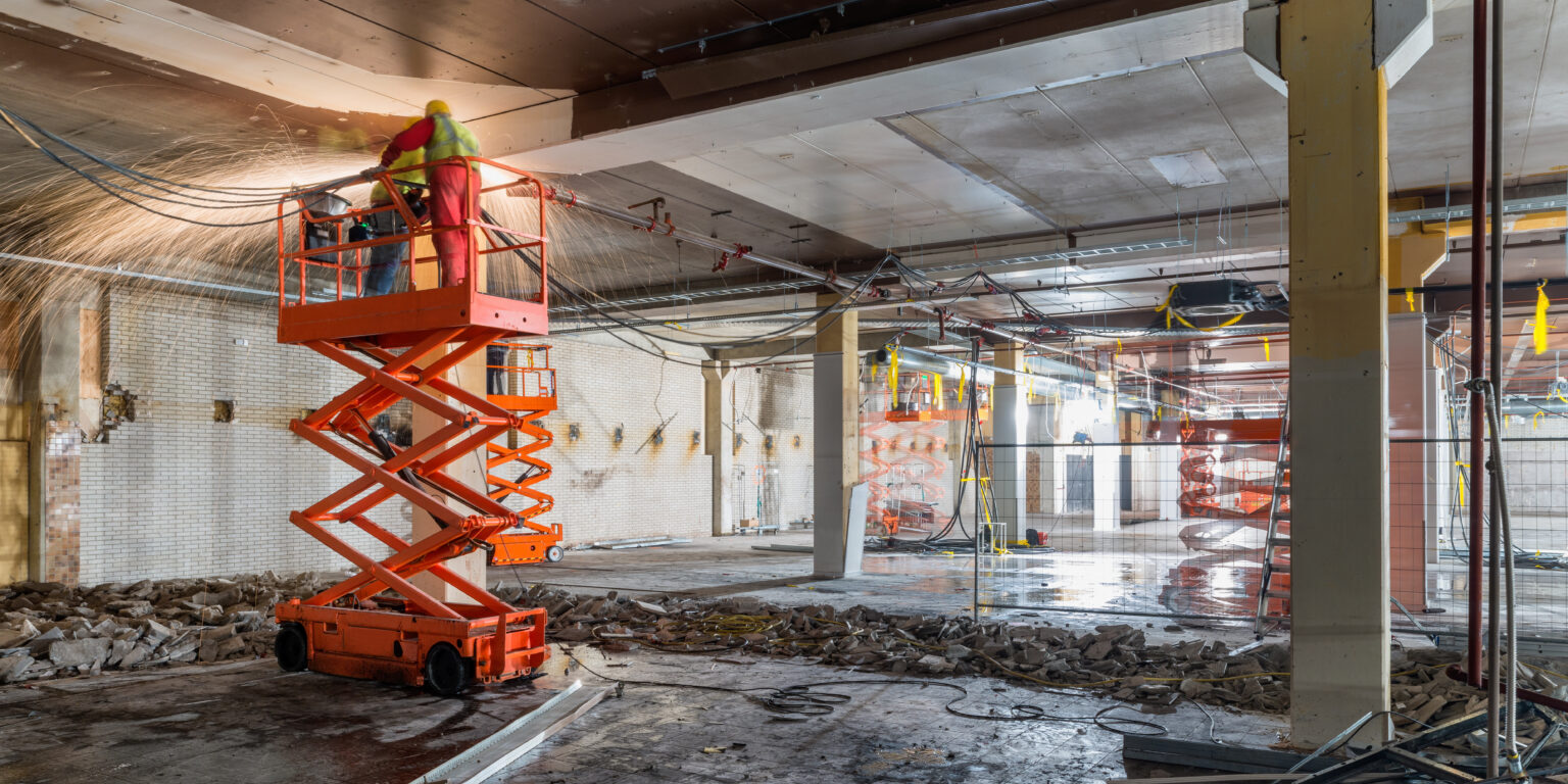 Manual Workers welding at Construction site while standing on scissor lift