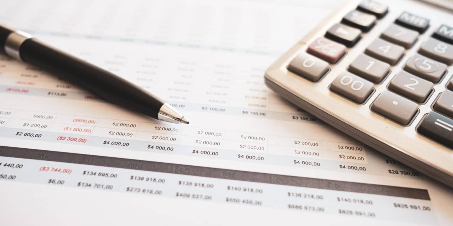personal finance scene featuring a calculator, pen, glasses,