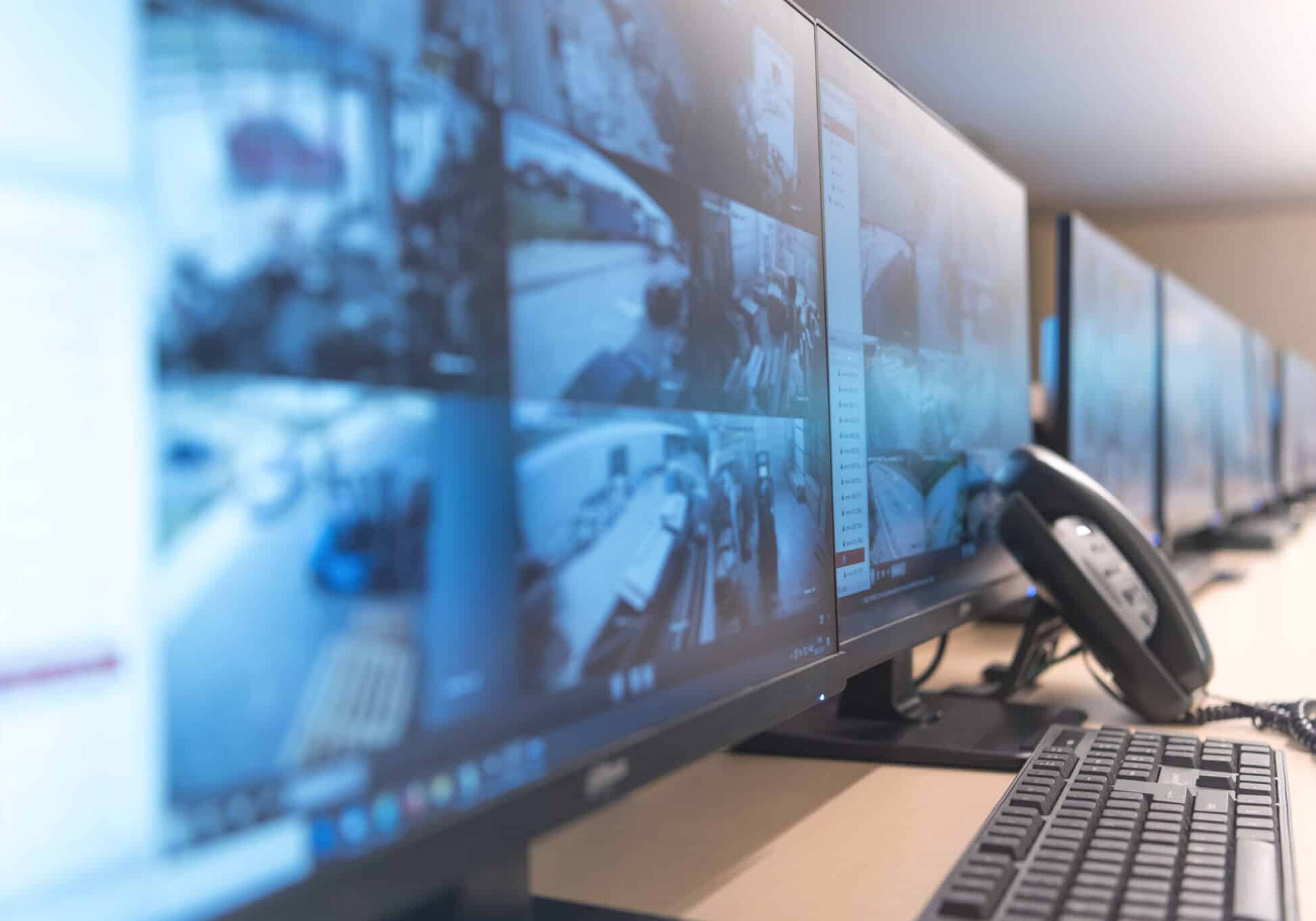 Security guard monitoring modern CCTV cameras in surveillance room.